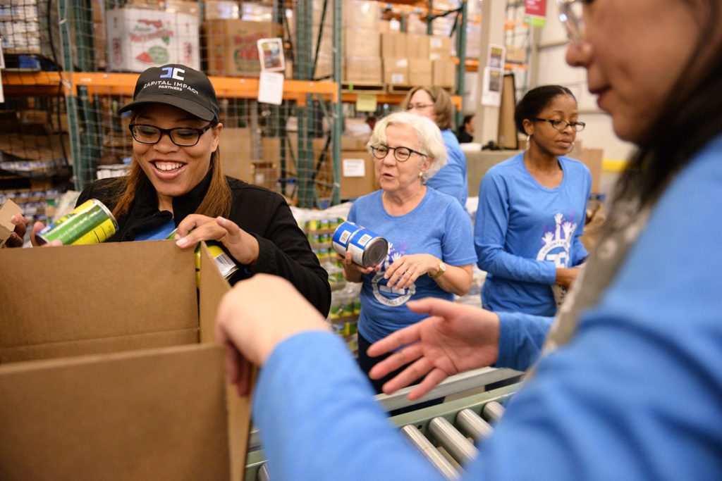 Capital Impact staff pack boxes with non-perishable food for families experiencing.